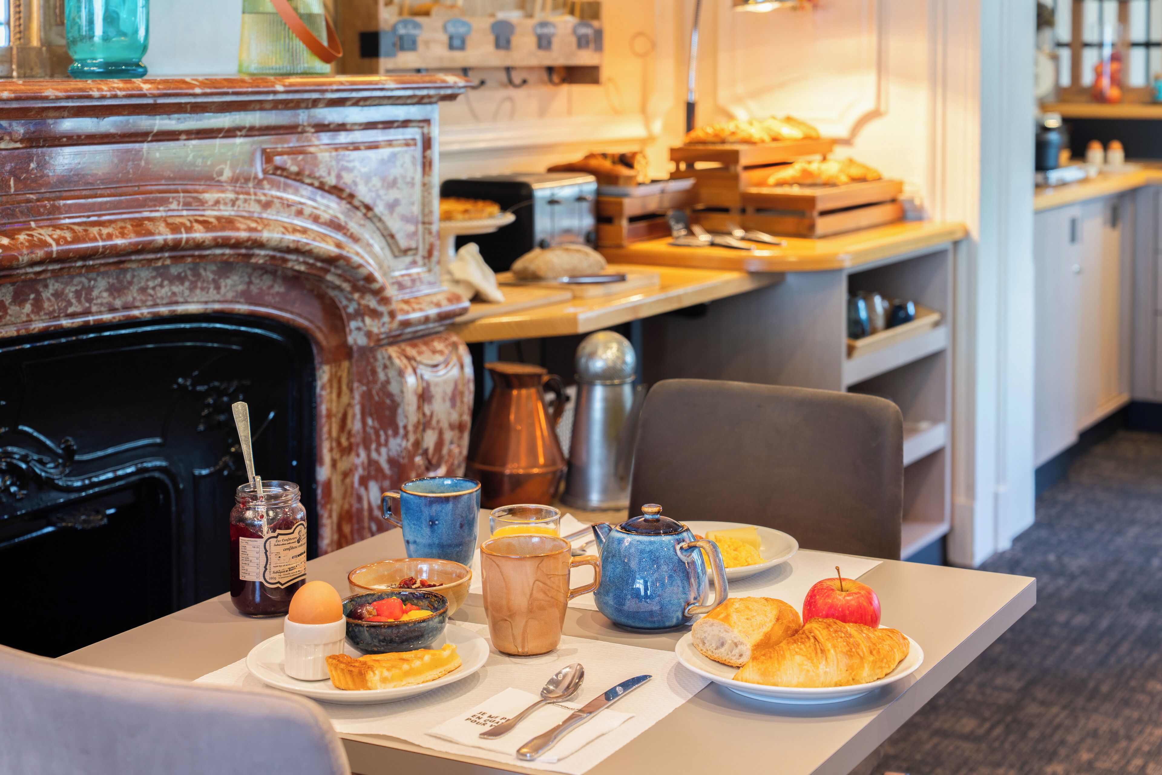 A breakfast table with various food items and a coffee pot.