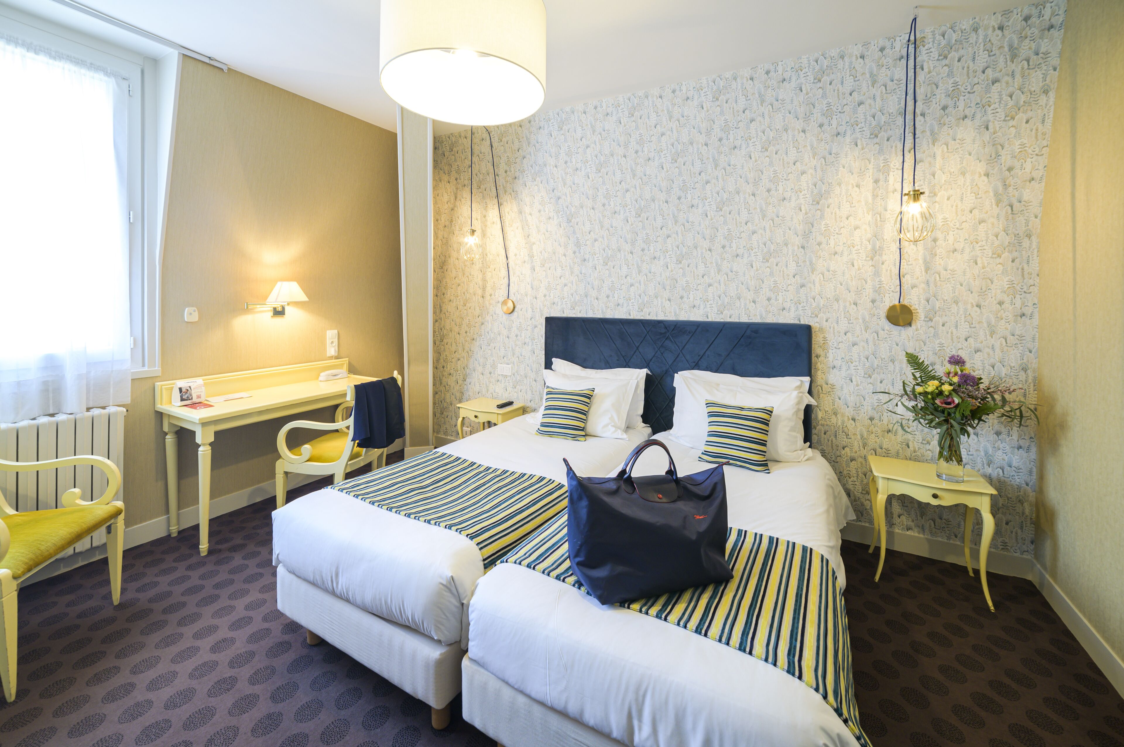 Habitación de hotel con una cama grande, dos mesitas de noche, un escritorio, una silla y un radiador.