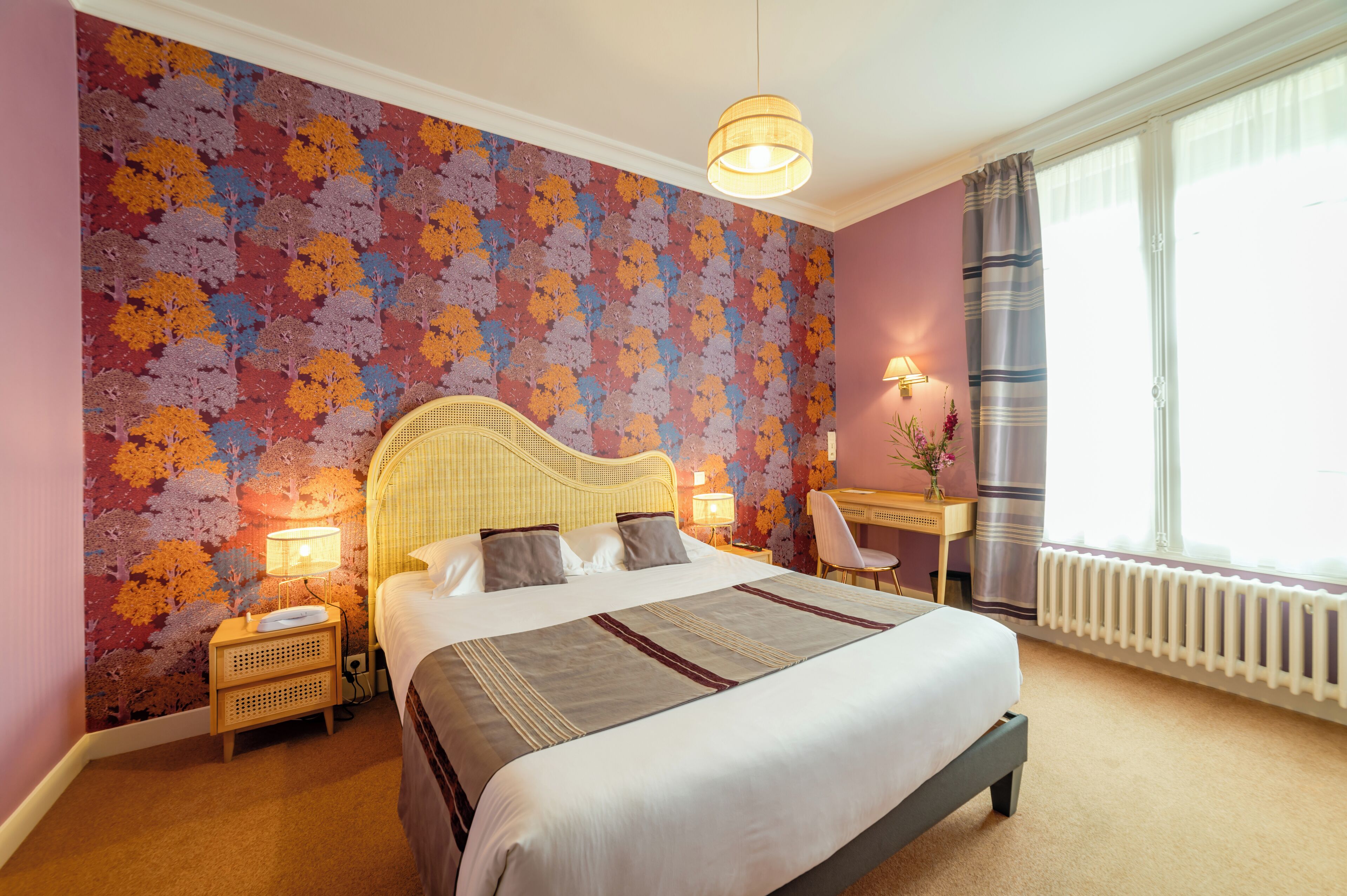 Ein Hotelzimmer mit einem großen Bett, einem Schreibtisch, einem Stuhl und einem Fenster mit Vorhängen.