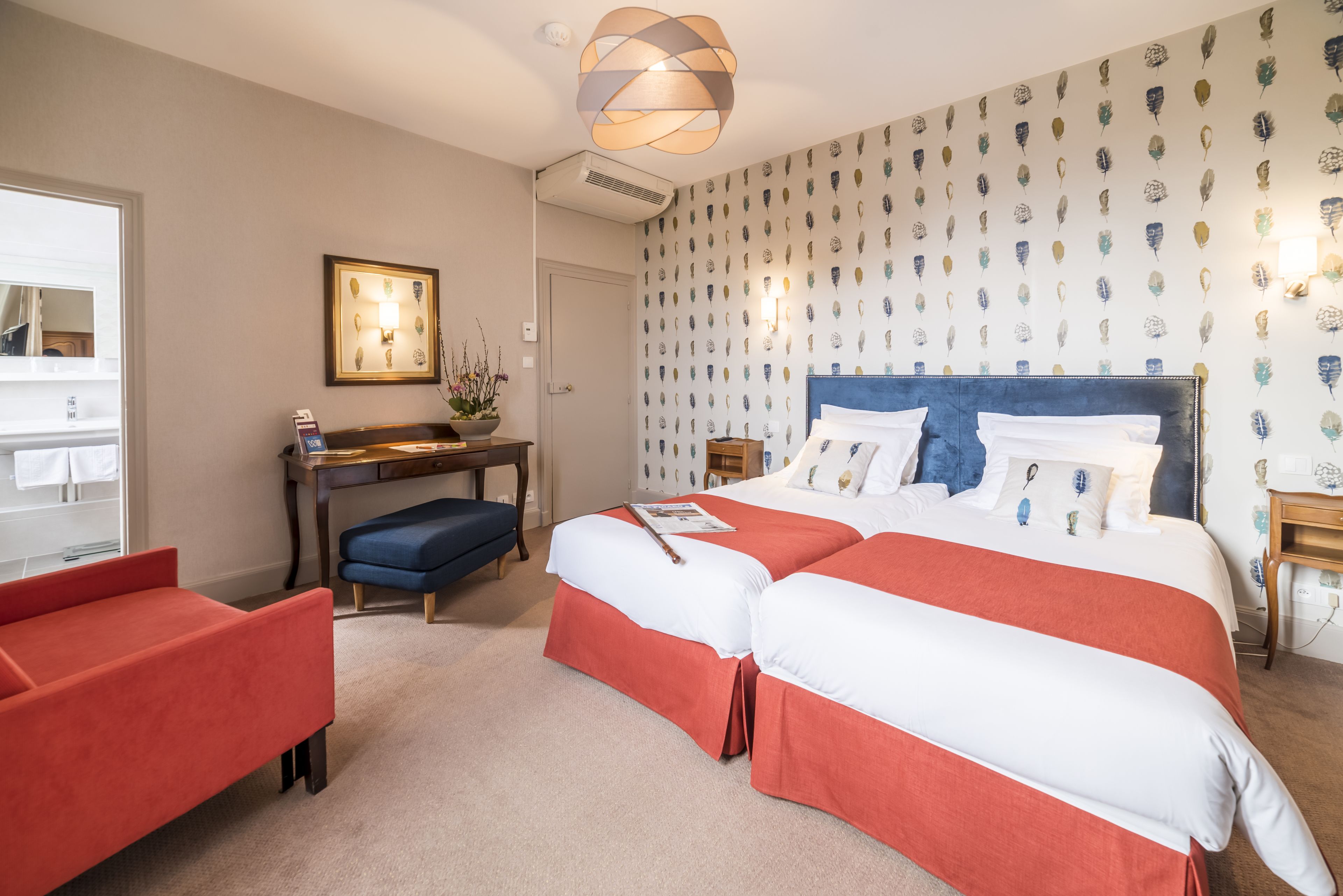 A hotel room with two beds, a desk, and a chair.