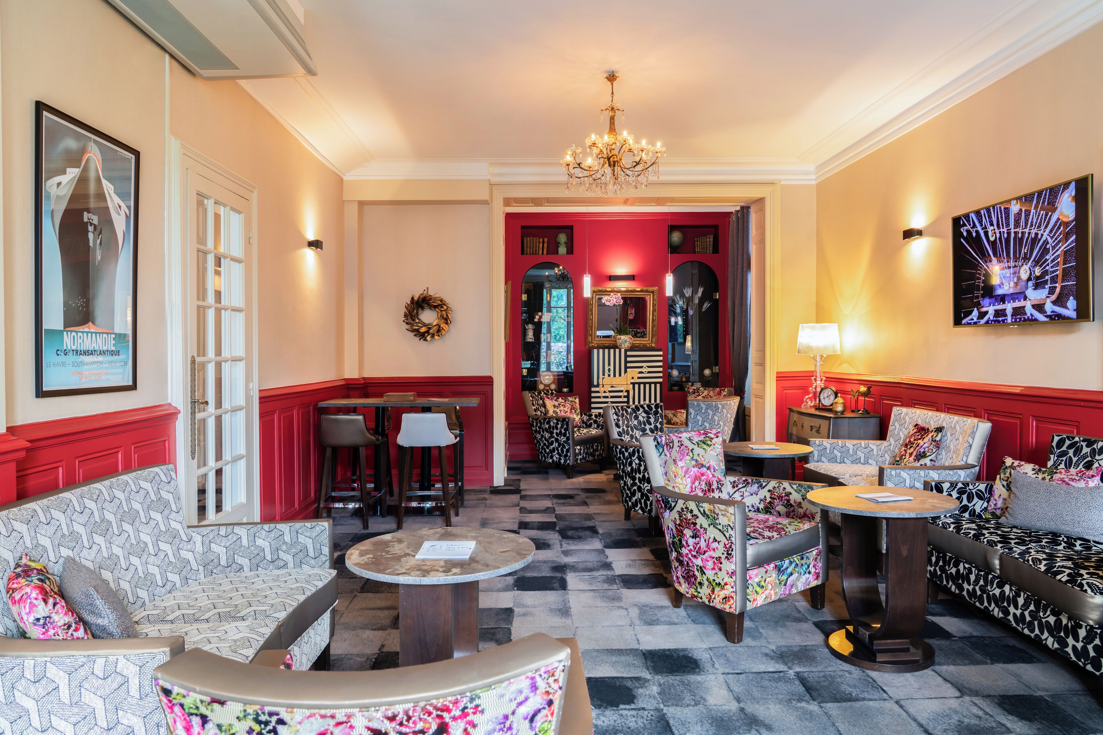 A hotel lobby with a checkered floor, red and white walls, and a variety of seating options including sofas and armchairs.
