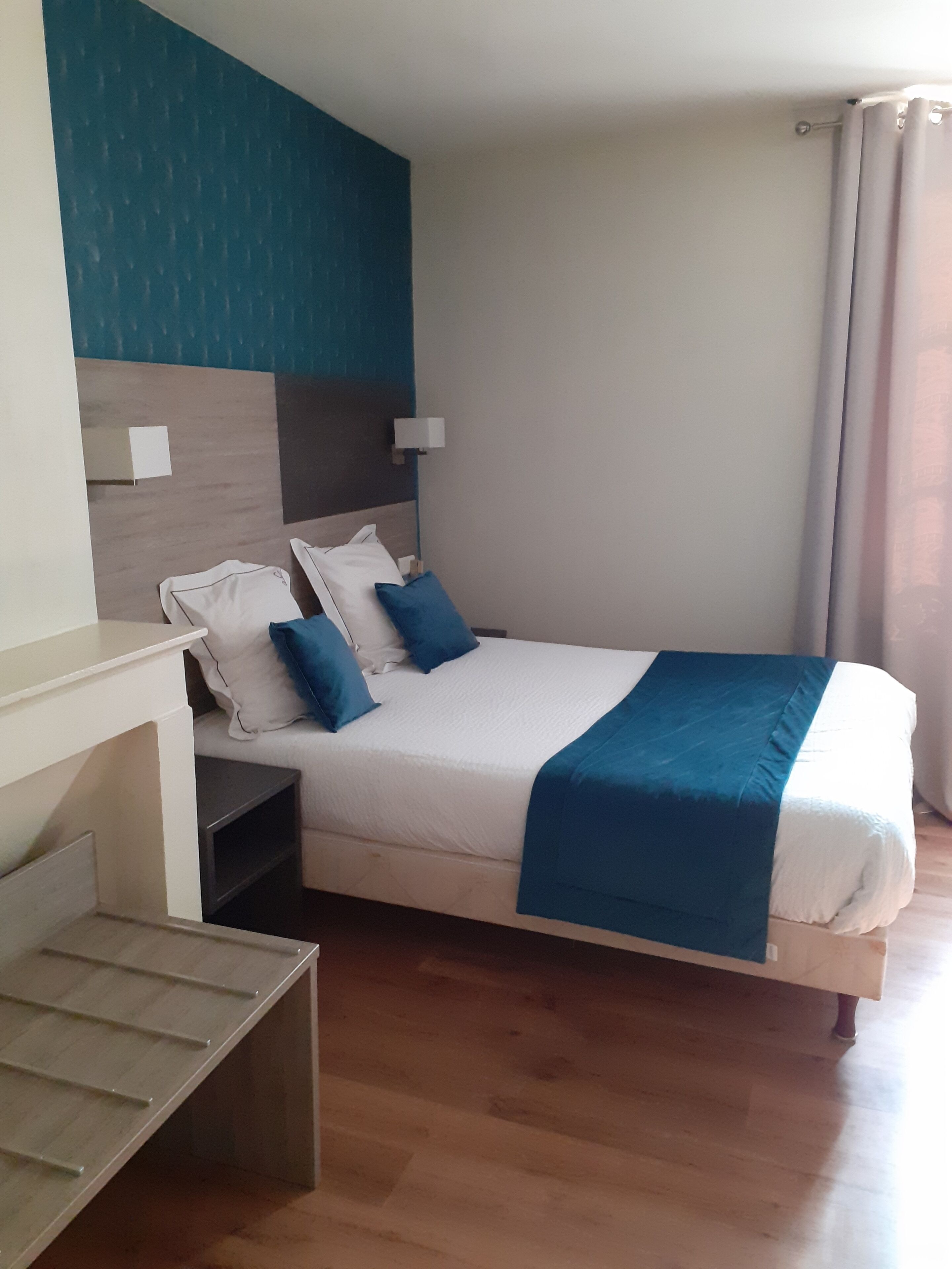 A neatly arranged bedroom with a bed, bedside tables, a nightstand, and a wall-mounted lamp.