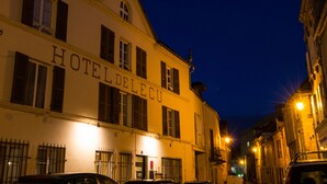 Um hotel chamado HOTEL DELLECU com fachada clássica, várias janelas e vista para a rua.