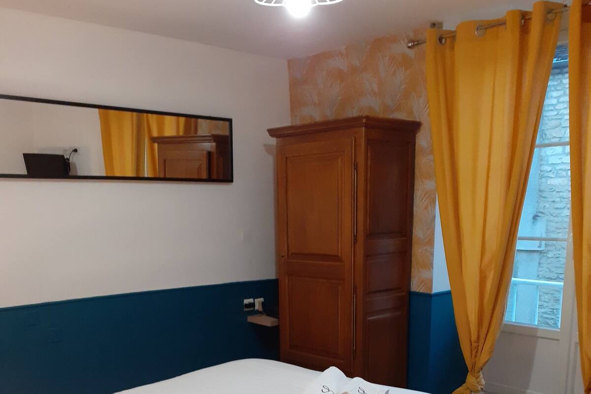 A bedroom with a bed, a wardrobe, a nightstand, and a window with curtains.