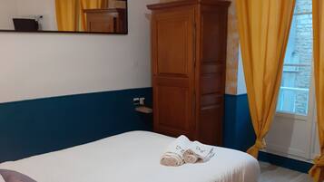 A bedroom with a bed, a wardrobe, a nightstand, and a window with curtains.