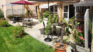Un patio al aire libre con mesas, sillas, sombrillas y plantas en macetas.