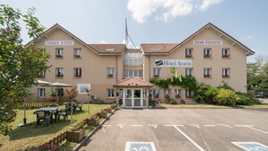Un hotel con una entrada central, dos alas identificadas como "SOIREE ETAPE" y "DEMI-PENSION", y un letrero que dice "Hotel Acacia".