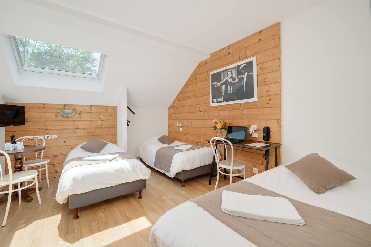 A modern hotel room with two beds, a desk, and a chair. There is a window and a poster on the wall.