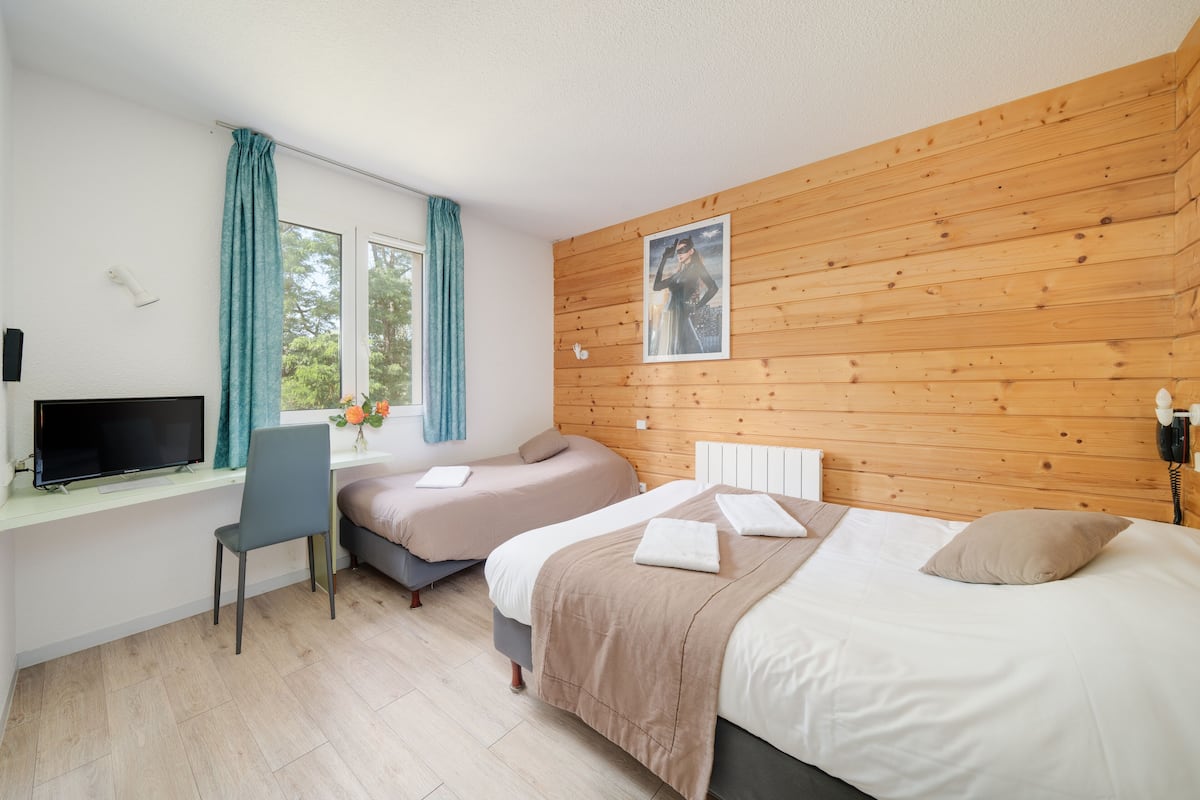 A bedroom with two beds, a desk, a chair, and a TV.