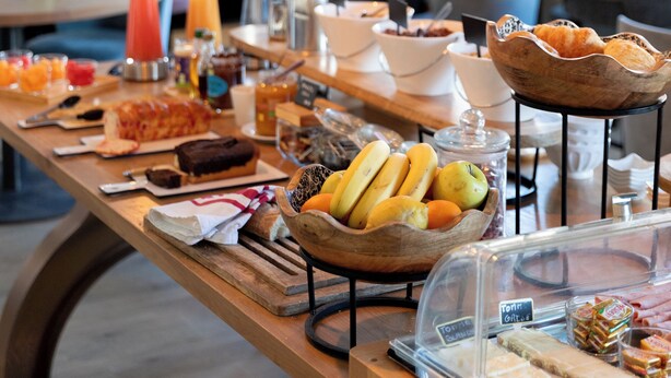 Un buffet de petit-déjeuner proposant une variété de plats, ainsi qu’un espace repas avec des chaises et des tables bleues.