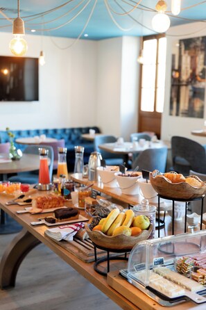 A breakfast buffet with various food items and a seating area with blue chairs and tables. -  Grand Hôtel de la Gare Toulon – Boutique Hôtel  (Toulon)