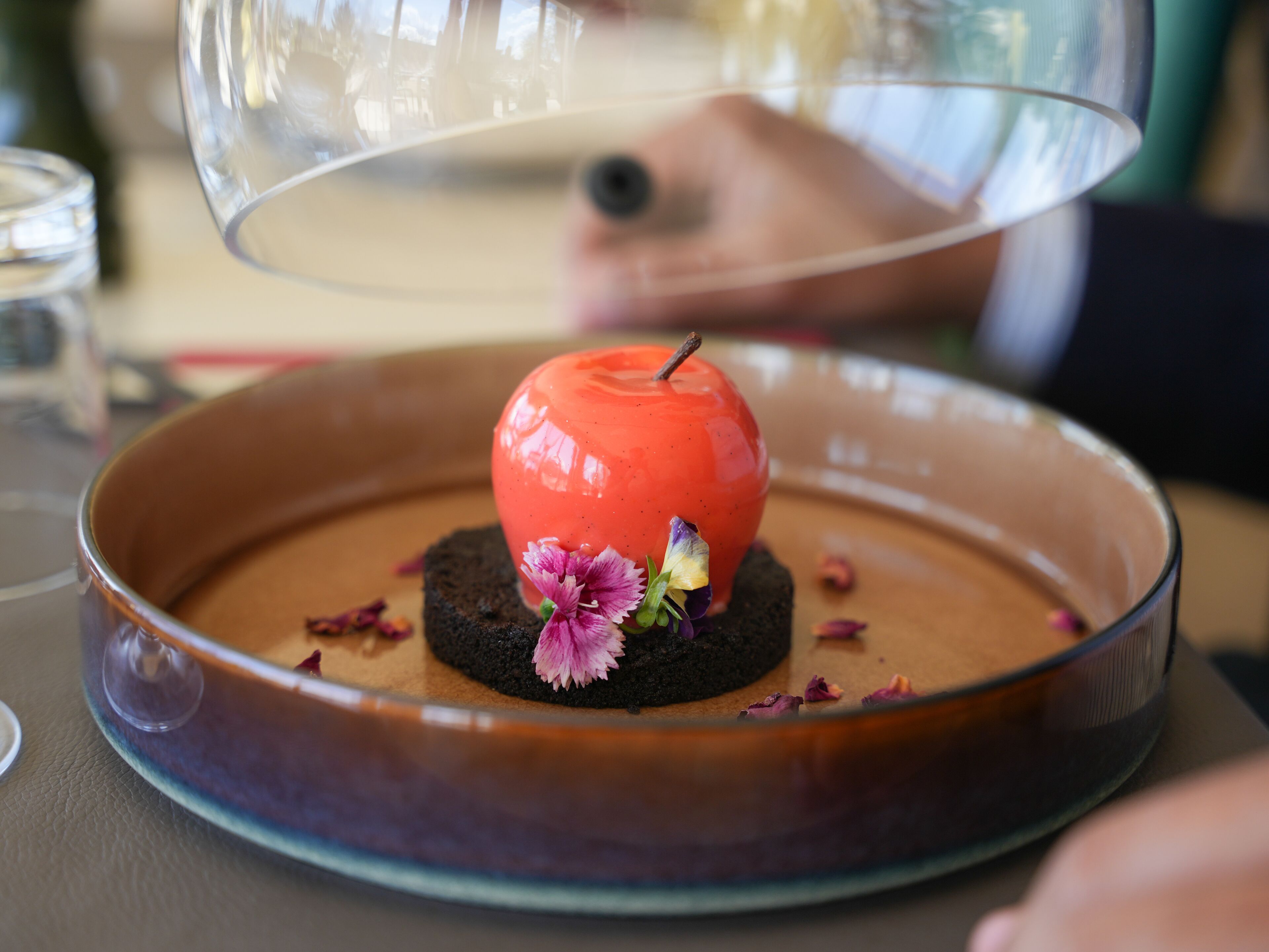 Un postre en un plato cubierto con una campana de cristal.