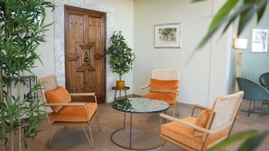 Un rincón interior acogedor con dos sillones tapizados color naranja, una mesa redonda y una planta en maceta.