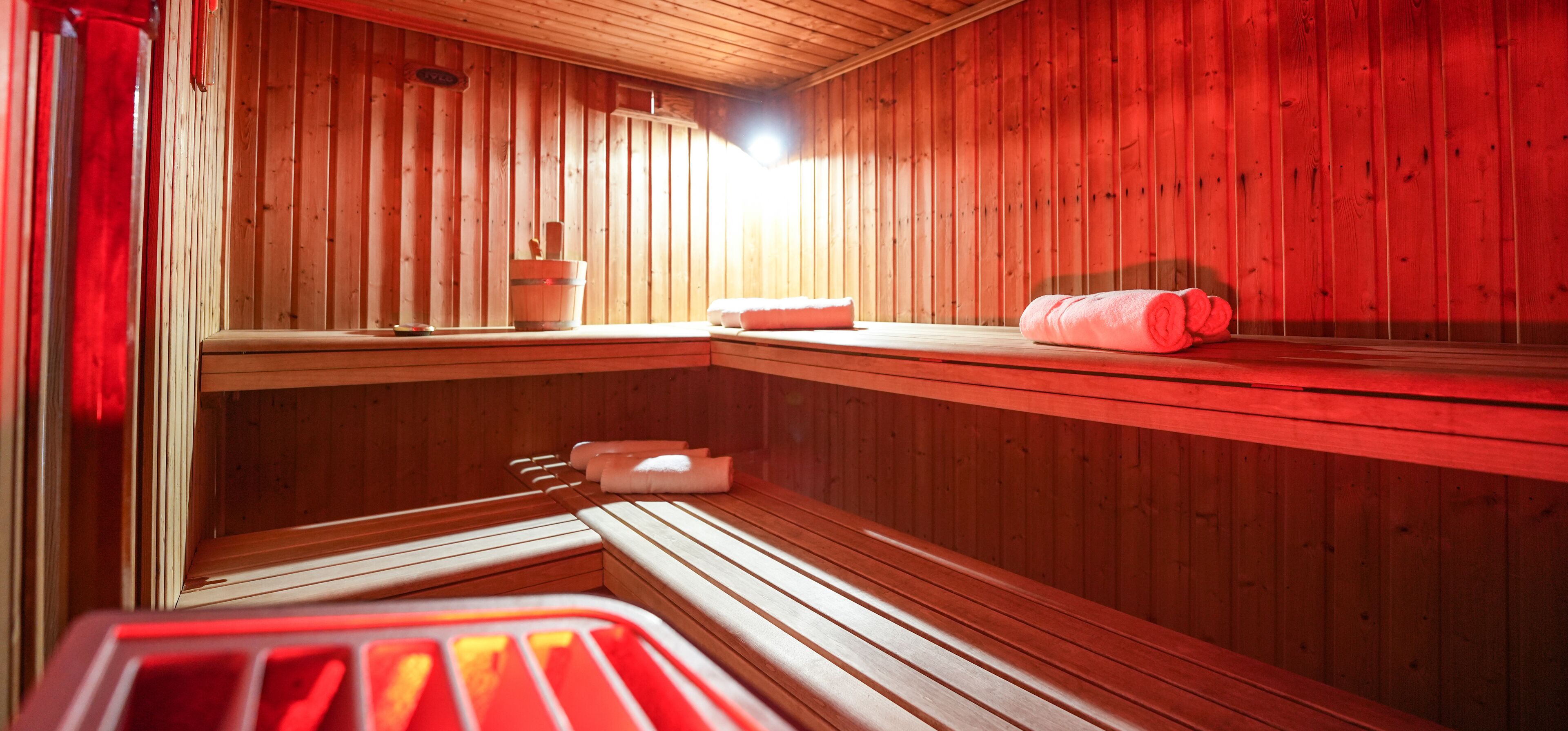 Una sala de sauna con paredes de madera, un banco y un asiento.