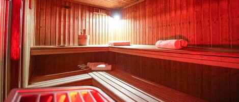 Una sala de sauna con paredes de madera, un banco y un asiento.