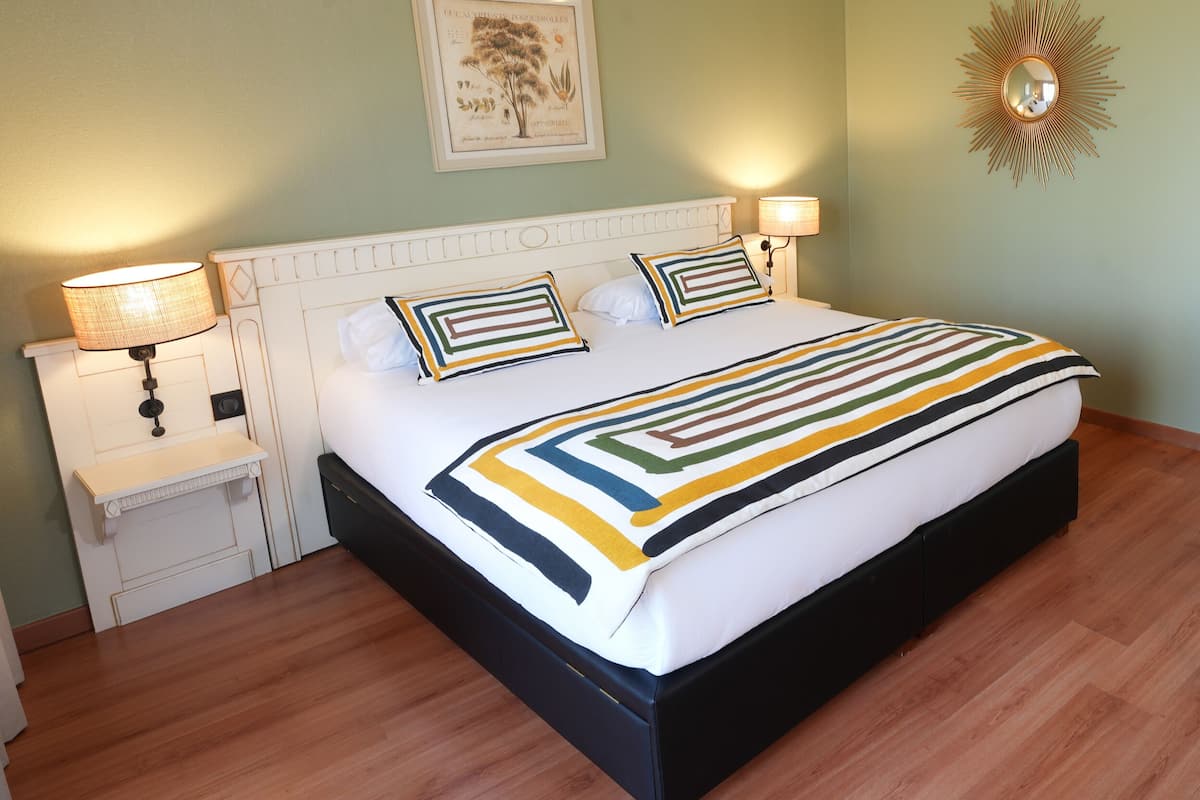 A neatly arranged bedroom with a bed, bedside tables, a mirror, and a breakfast tray.