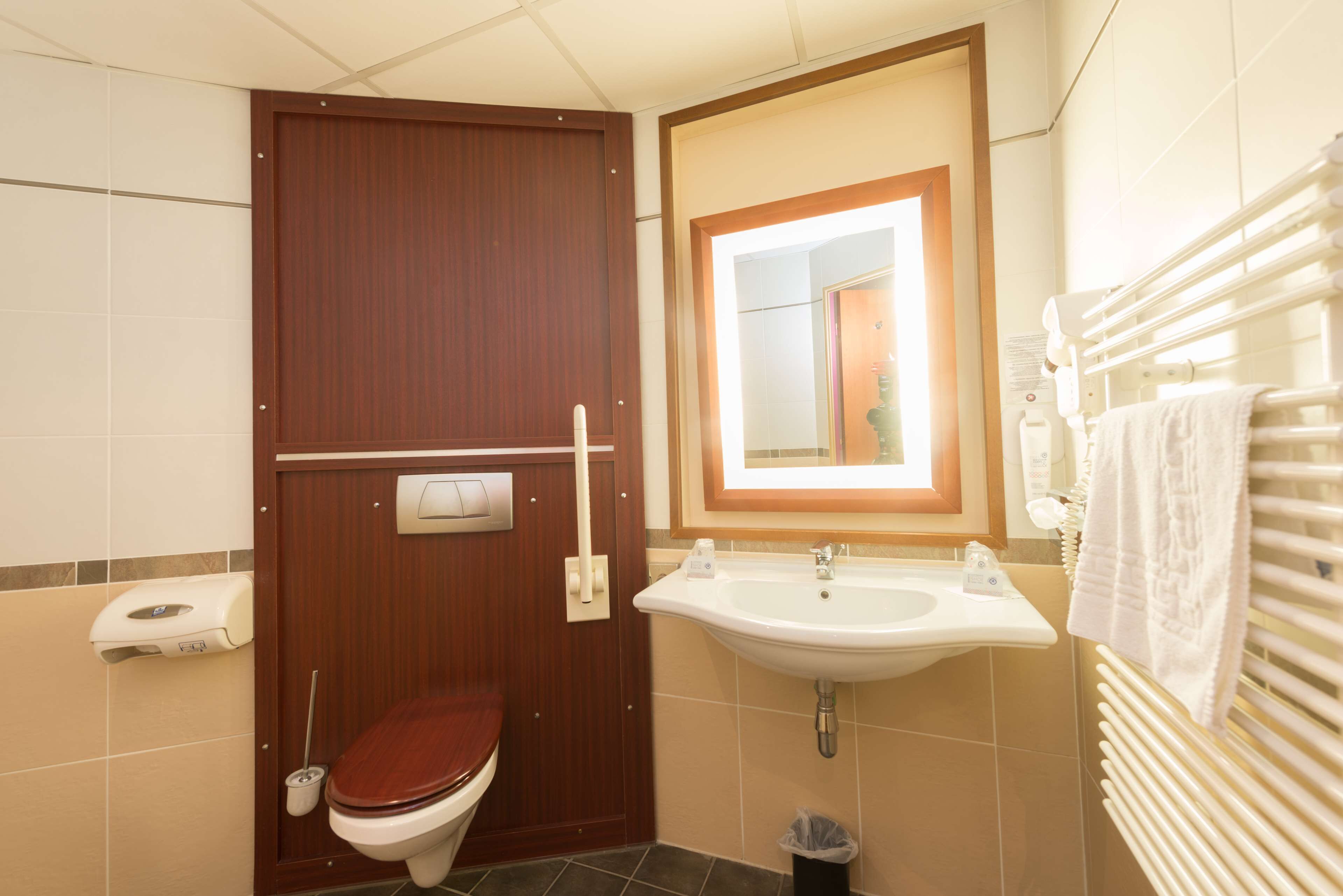 Un baño pequeño con una puerta de madera, un lavabo blanco y un espejo.