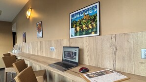 En receptionsdisk med en bærbar computer, mus og en menu. Der er fletstole og et indrammet billede på væggen.