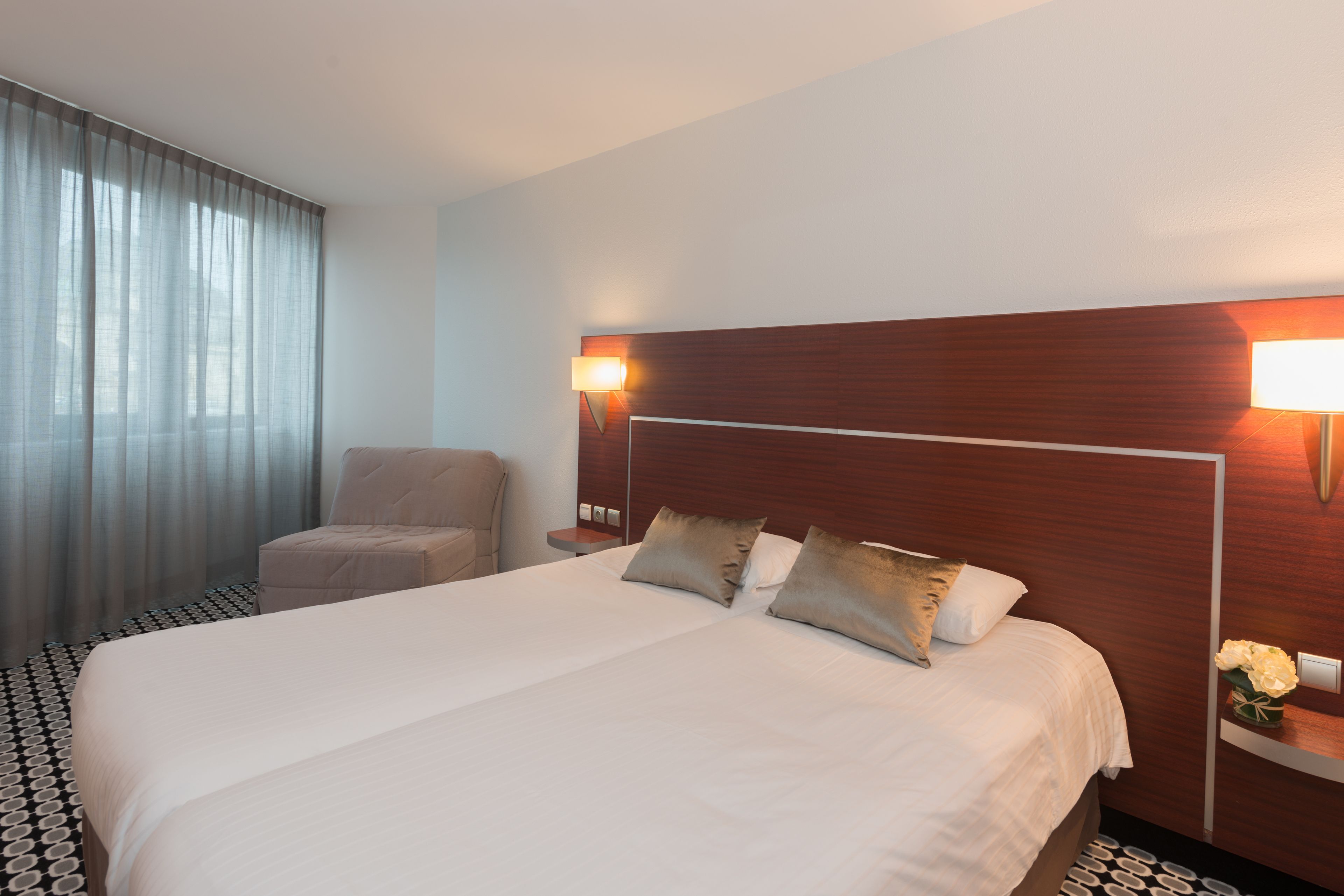 Een hotelkamer met een groot bed, een stoel, een nachtkastje en een lamp.