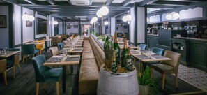 A restaurant with long communal tables, individual booths, and a bar area. - Kyriad Limoges Centre - Gare - Atrium (Limoges)