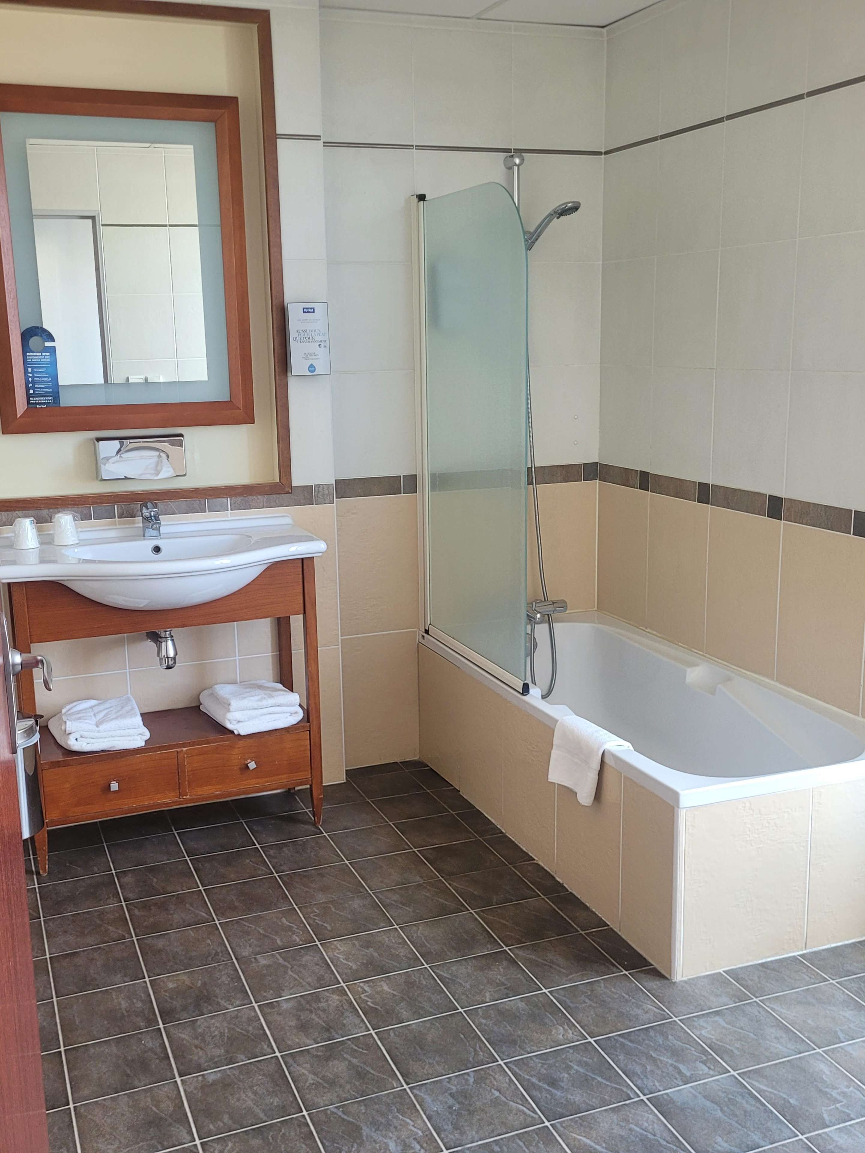 A bathroom with a bathtub, a glass-enclosed shower, a vanity with a sink, and a mirror.