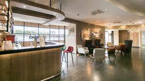 Et moderne barområde med en buet bar, siddepladser med forskellige stole, og store vinduer med udsigt over byen.