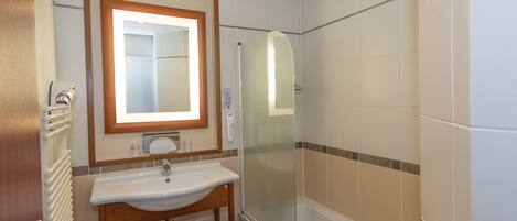 A bathroom with a sink, mirror, towel rack, and shower.
