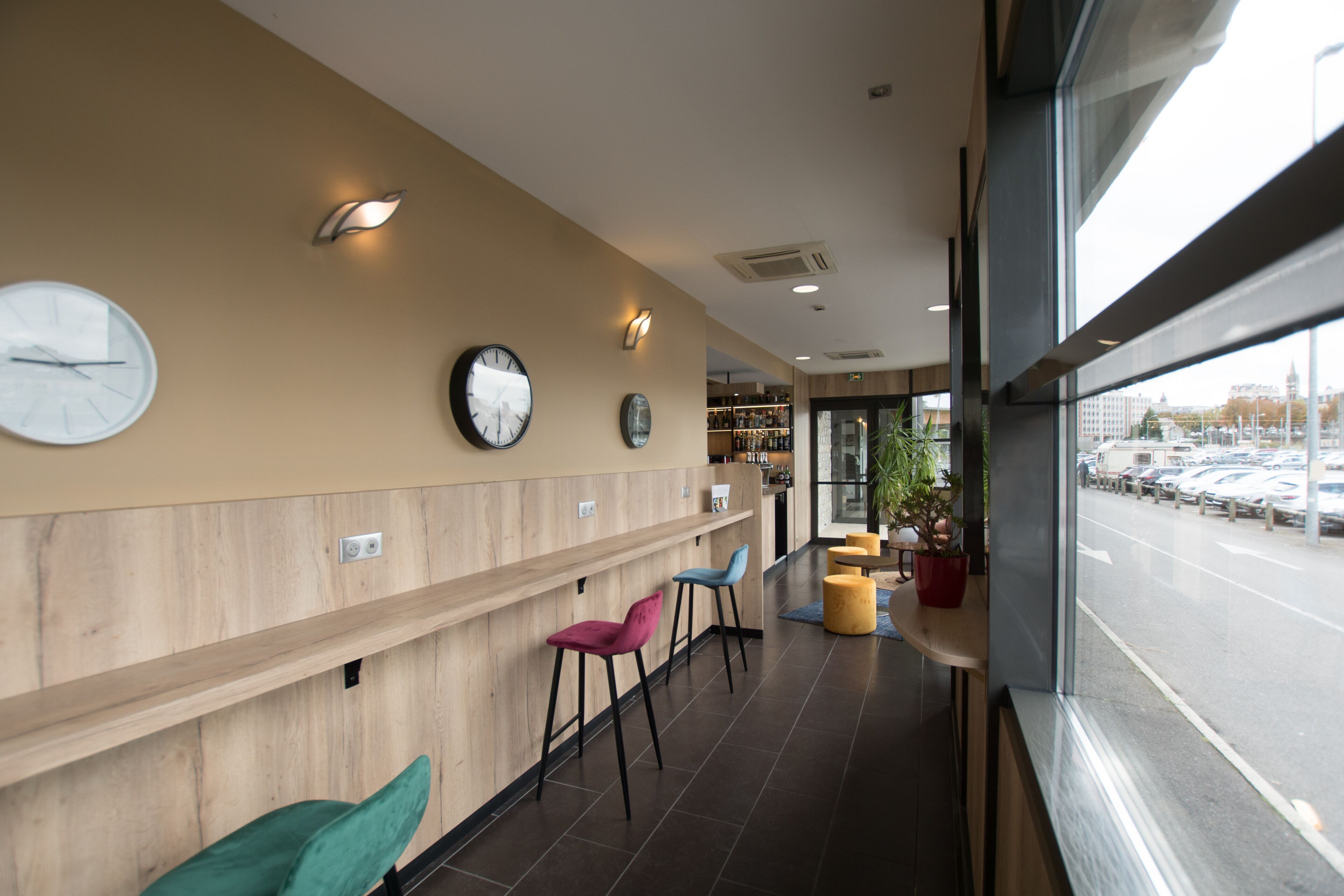 A modern interior with a wooden reception desk, multiple chairs, and wall clocks.
