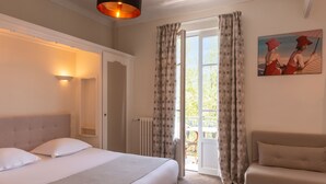 Een slaapkamer met een bed, een bank, een schilderij en uitzicht door de gordijnen.