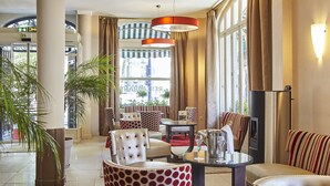 Een hotel lobby met een zithoek, grote ramen en uitzicht op de straat.