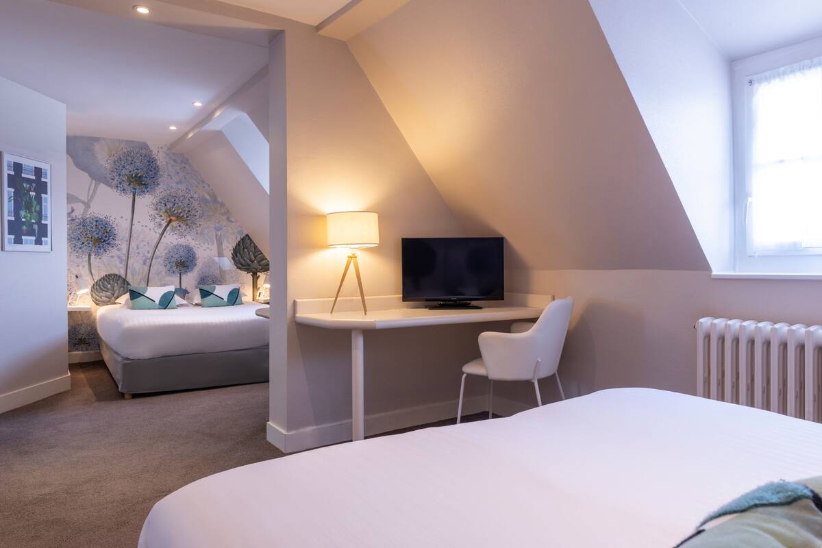 Une chambre moderne comprenant un lit, un bureau, une chaise, un téléviseur et un radiateur.