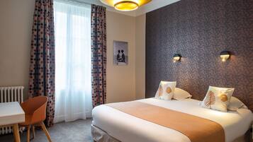 A hotel room with a large bed, a desk, and a chair.