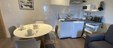 A compact living space with a dining area, kitchenette, and a sofa.