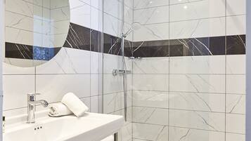 A modern bathroom with a glass-enclosed shower, a white sink with chrome fixtures, and a large mirror.