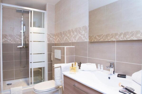A modern bathroom with a shower, toilet, and vanity.