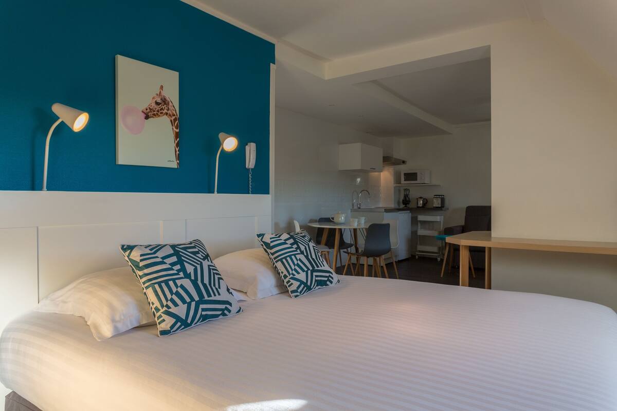 Une chambre d’hôtel équipée d’un lit, de deux oreillers, d’un bureau, d’une chaise, d’un four à micro-ondes et d’un lavabo.