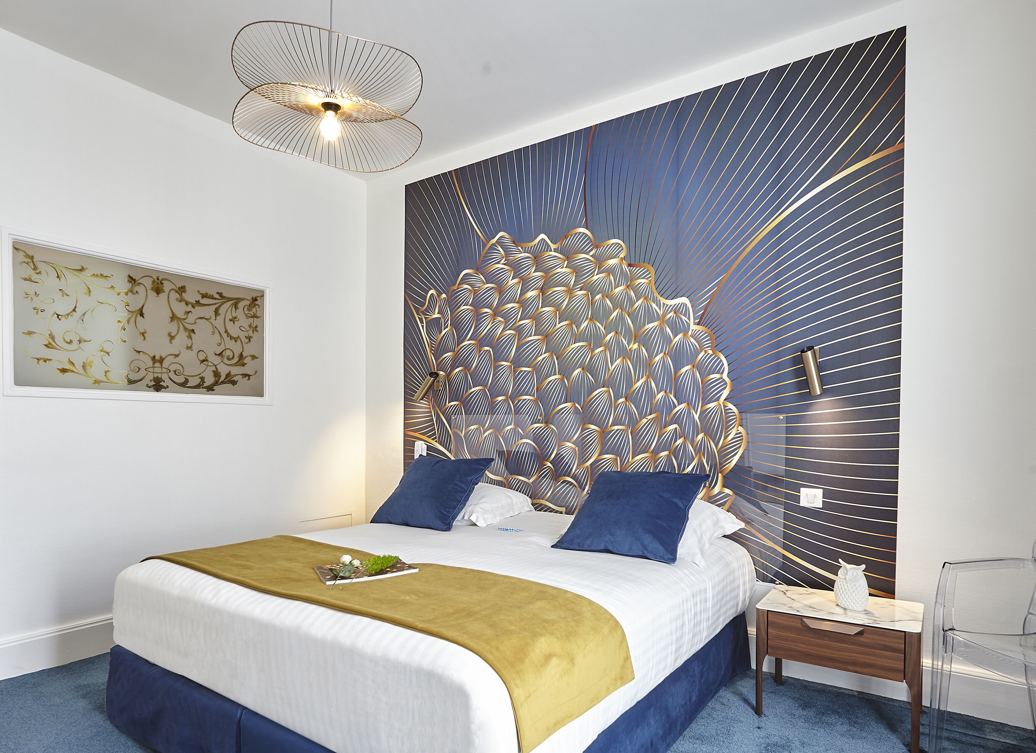 A modern bedroom with a large bed, a decorative headboard, a bedside table, and a clear chair.