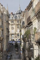 Una calle estrecha bordeada de edificios históricos, con balcones, fachadas ornamentadas y una cúpula destacada.