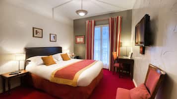 Une chambre d’hôtel avec un grand lit, un bureau, une chaise et un téléviseur fixé au mur.