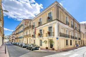 Un hotel con una fila de coches aparcados, cielo despejado y un paso de peatones.