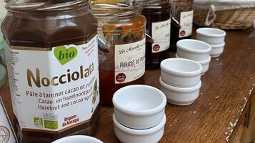 Une variété de produits alimentaires, notamment des pots de Nocciolata et d’autres pâtes à tartiner, disposés sur une table en bois.