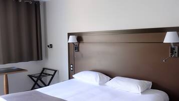 Une chambre d’hôtel avec un grand lit, deux lampes de chevet, une petite table et une chaise.