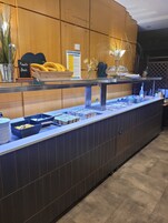 A buffet setup with various food items and a sign indicating 'Fruits frais'.