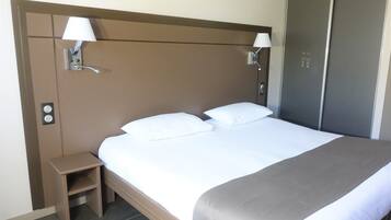 Ein Hotelzimmer mit einem großen Bett, zwei Nachttischlampen, einem Nachttisch und einem Kleiderschrank.