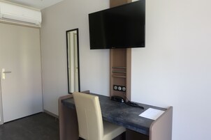 A small office space with a desk, chair, and a mounted flat-screen TV.