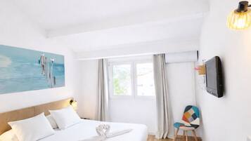 Una camera d'albergo con un letto, una scrivania con una sedia, una televisione e un quadro appeso al muro.