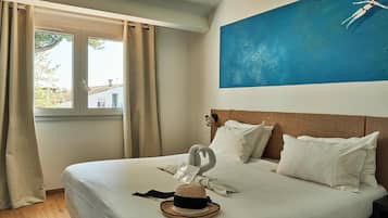 A hotel room with a bed, a window with curtains, a wall-mounted phone, and a painting of a woman swimming.