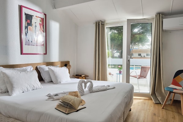 Hotelkamer met een bed, een ingelijst schilderij aan de muur, een raam met gordijnen en uitzicht op buiten.