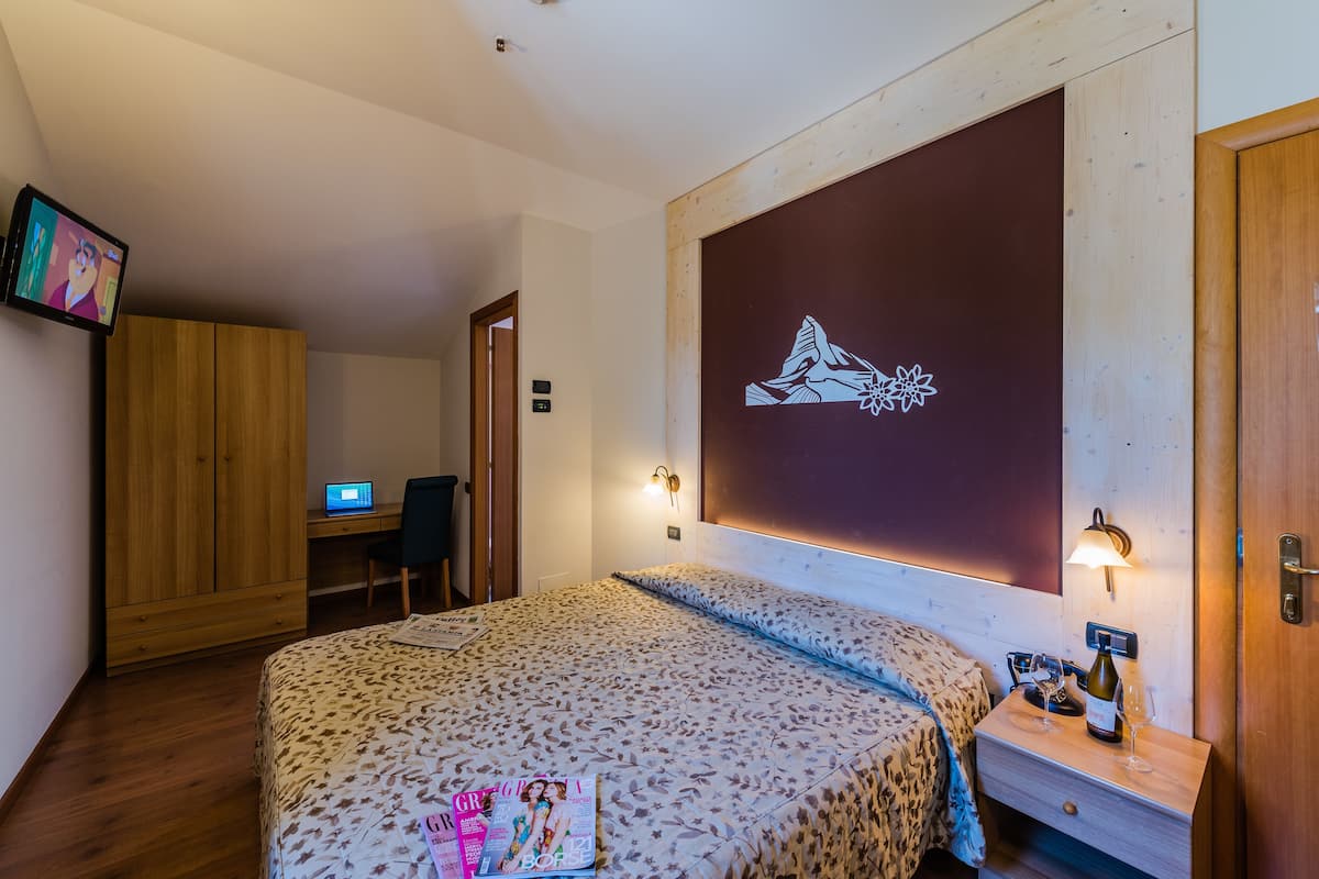 Une chambre à coucher avec un lit, un bureau et un ordinateur.