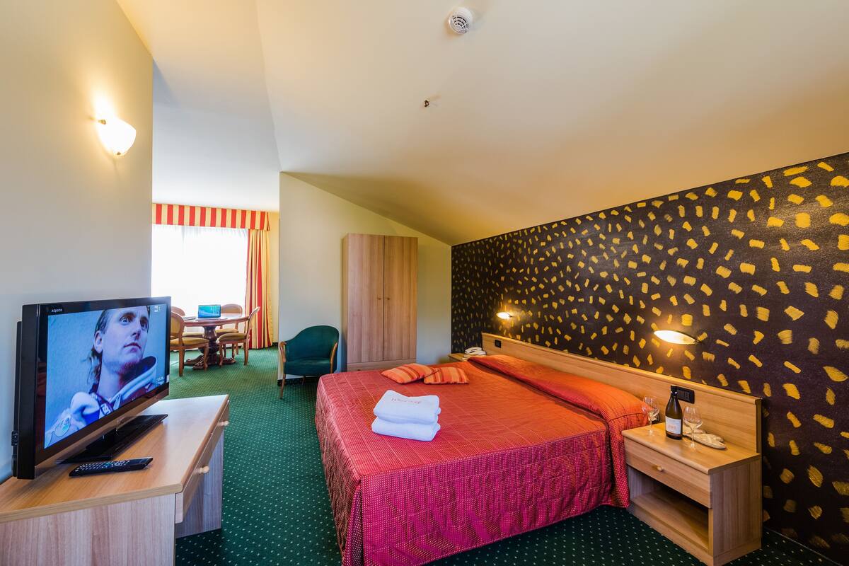 Une chambre d’hôtel équipée d’un lit, d’une télévision, d’un bureau, d’une chaise et d’une armoire.